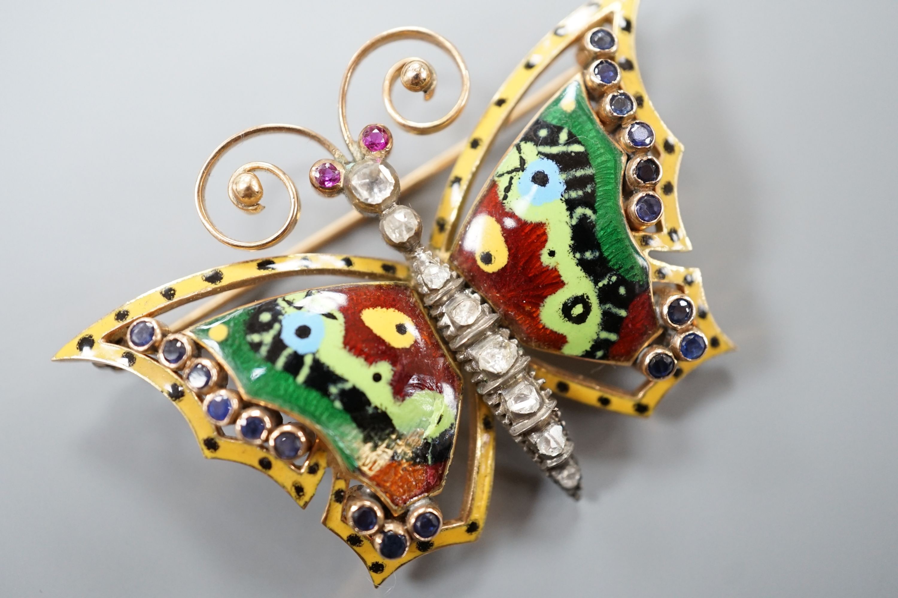 A continental yellow metal, polychrome enamel, rose cut diamond and gem set butterfly brooch (a.f.), width 50mm, gross weight 13.8 grams.